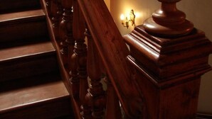 Een houten trap met decoratieve spijlen en een leuning.