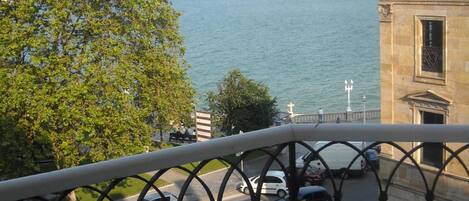 A balcony with a view of a river and buildings across it.