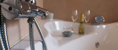 Un baño con bañera, ducha y una copa de vino en el borde.