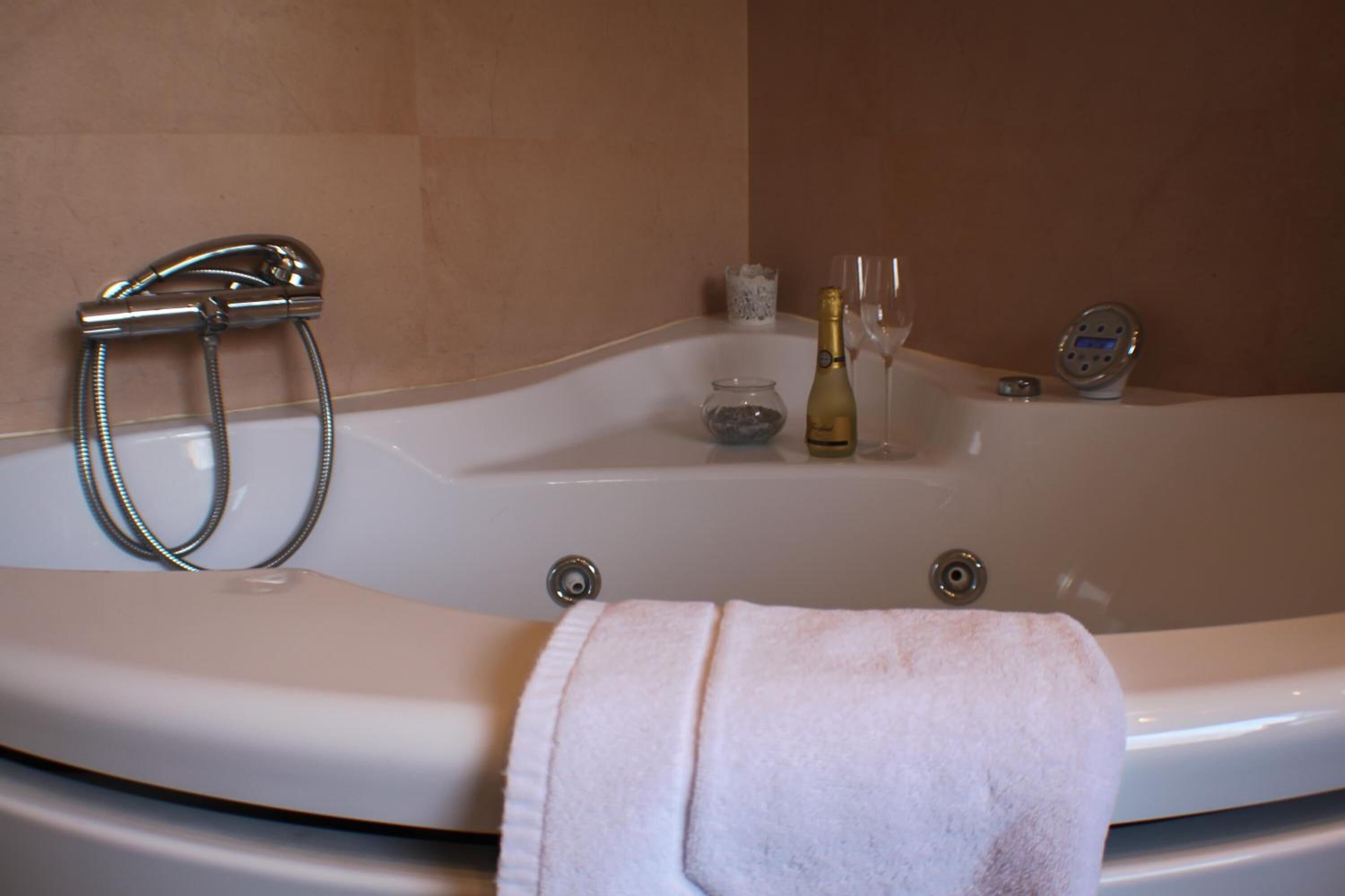 Un baño con bañera, ducha, una botella de champán y dos copas.
