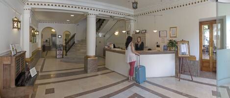 A lobby with a reception desk, a staircase, and a piano.