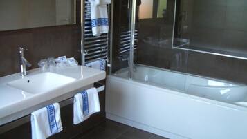 Un baño moderno con lavamanos doble, bañera y cabina de ducha con mampara de vidrio.