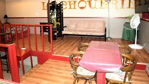 A dining area with a wooden table and chairs, a bench, and a wall with the word "LOCHOUERIE" in large letters. - Auberge Internationale La Vieille École (Sainte-Anne-des-Monts)