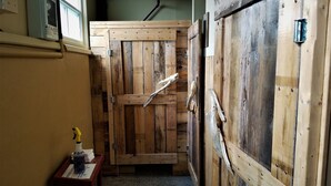 A narrow hallway with wooden doors and a small table with a bottle and a towel. - Auberge Internationale La Vieille École (Sainte-Anne-des-Monts)