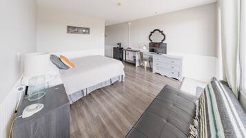 Ein modernes Hotelzimmer mit einem großen Bett, einem Schreibtisch, einem Stuhl und einer kleinen Küchenzeile.