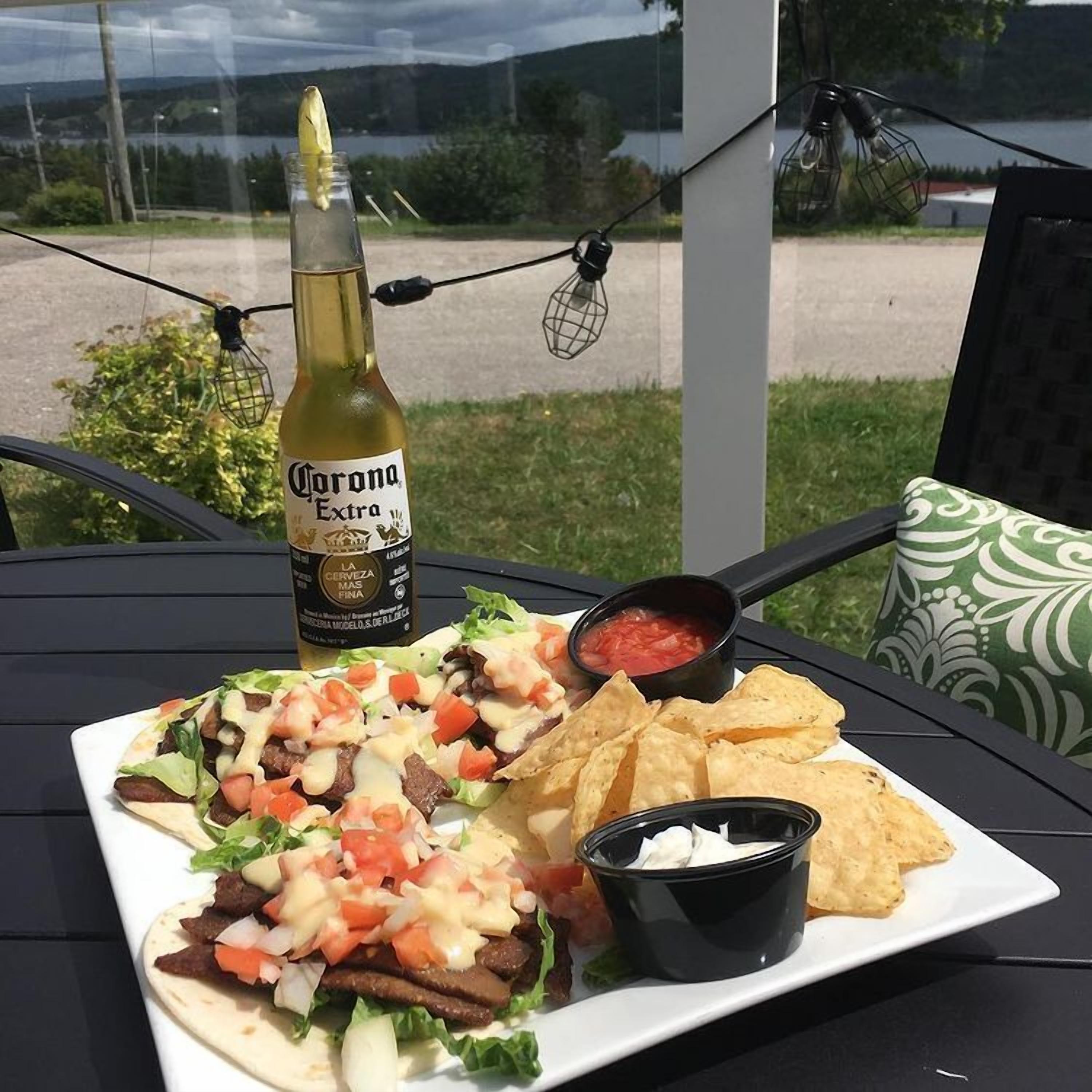 Een bord met taco's, een fles Corona Extra bier en een klein bakje salsa.