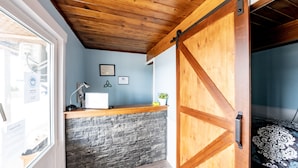 A room with a stone wall, wooden ceiling, and a bed with patterned bedding. - The Iona Heights Inn (Iona)