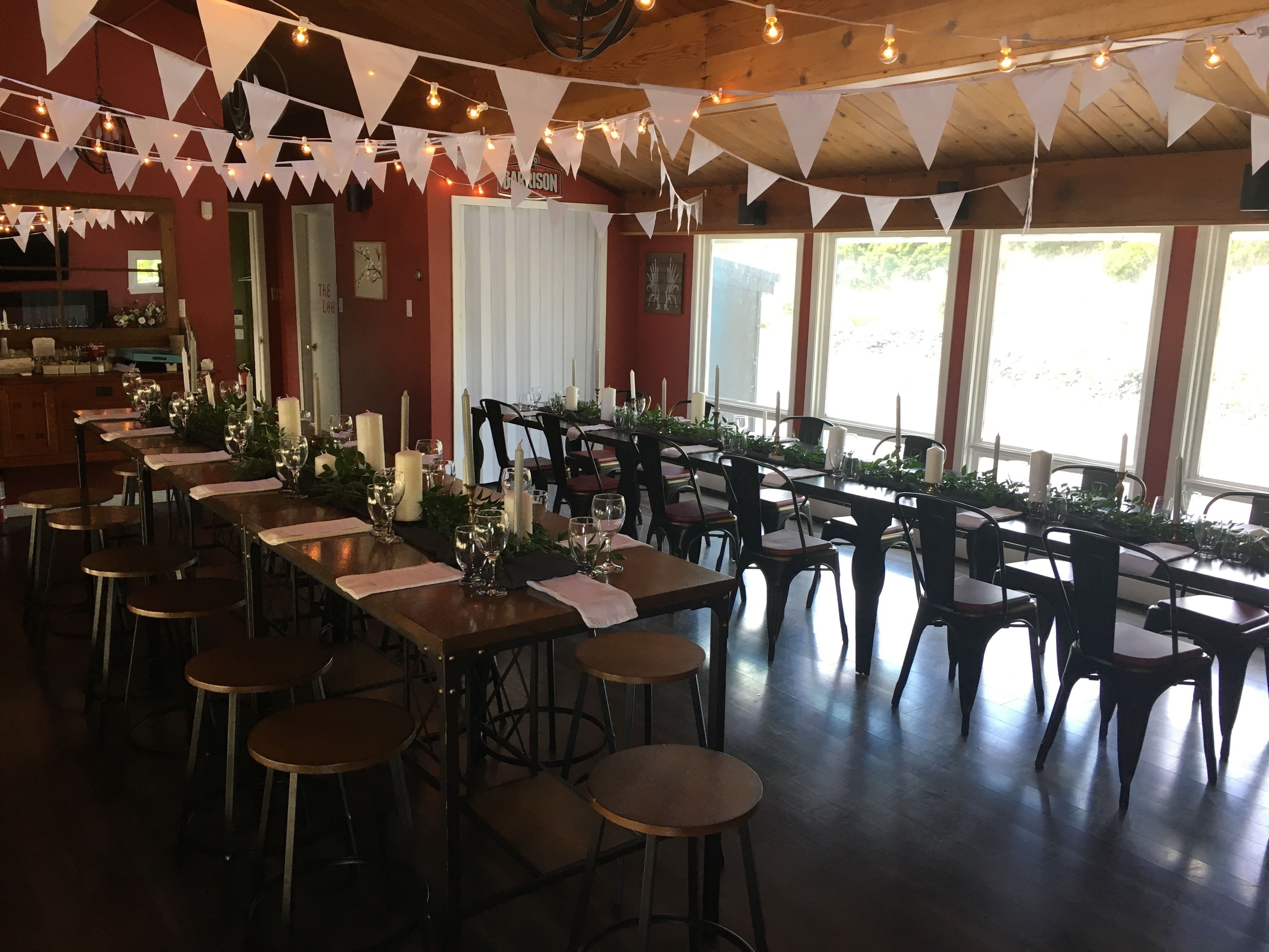 Ein Restaurant mit langen Gemeinschaftstischen, einzelnen Barhocker und einer Holzbalkendecke.