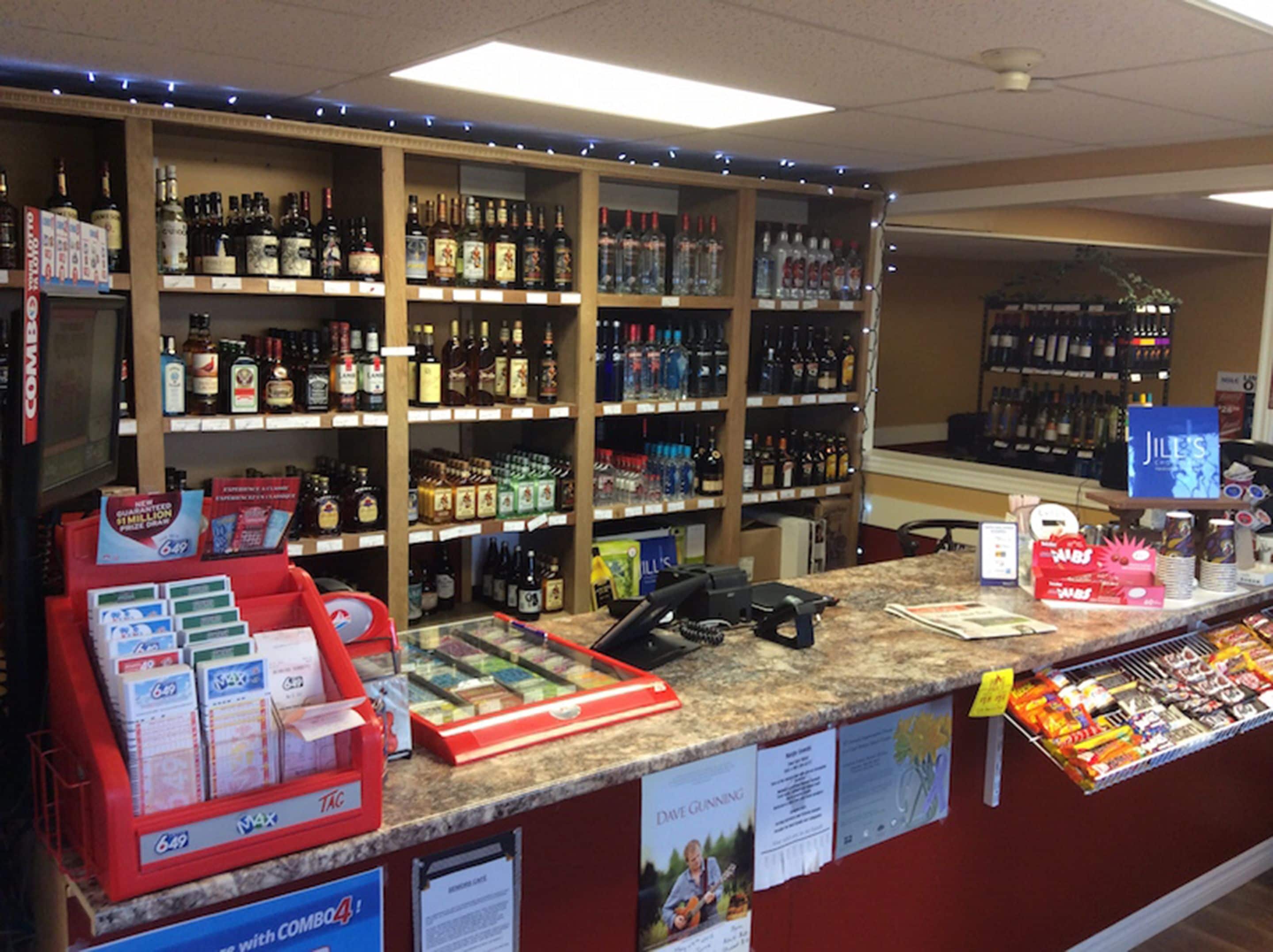 Une boutique de boissons alcoolisées dont les étagères sont remplies de différentes bouteilles et dont le comptoir est équipé d'une caisse enregistreuse et de matériel promotionnel.