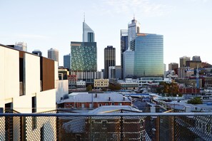 A cityscape with modern buildings, including a prominent skyscraper with a unique top and a glass facade.