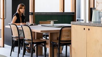 Un comedor moderno con una mesa de madera, sillas negras y una lámpara colgante grande.