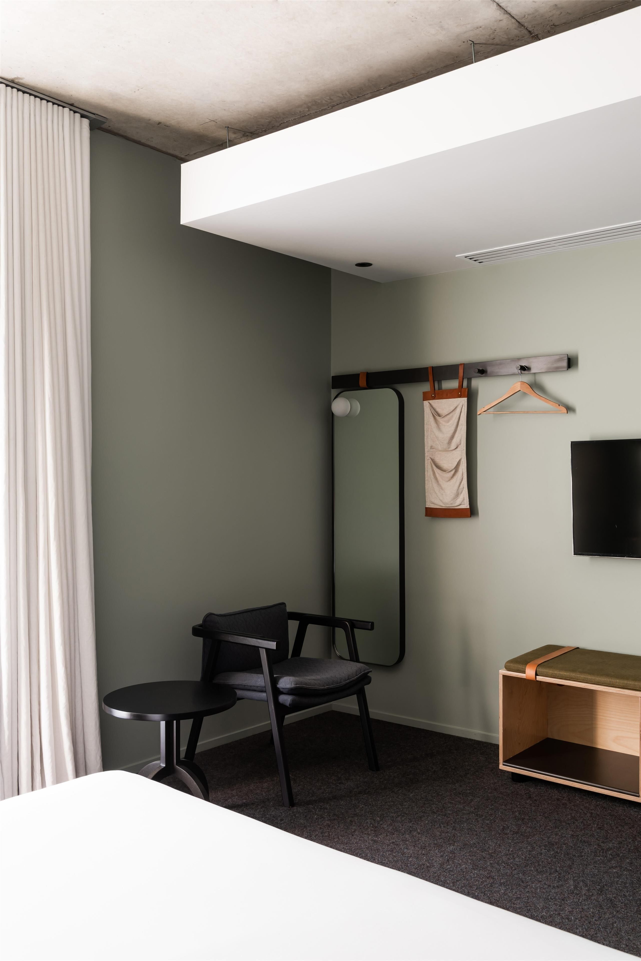 Una habitación moderna con escritorio, silla y un perchero.