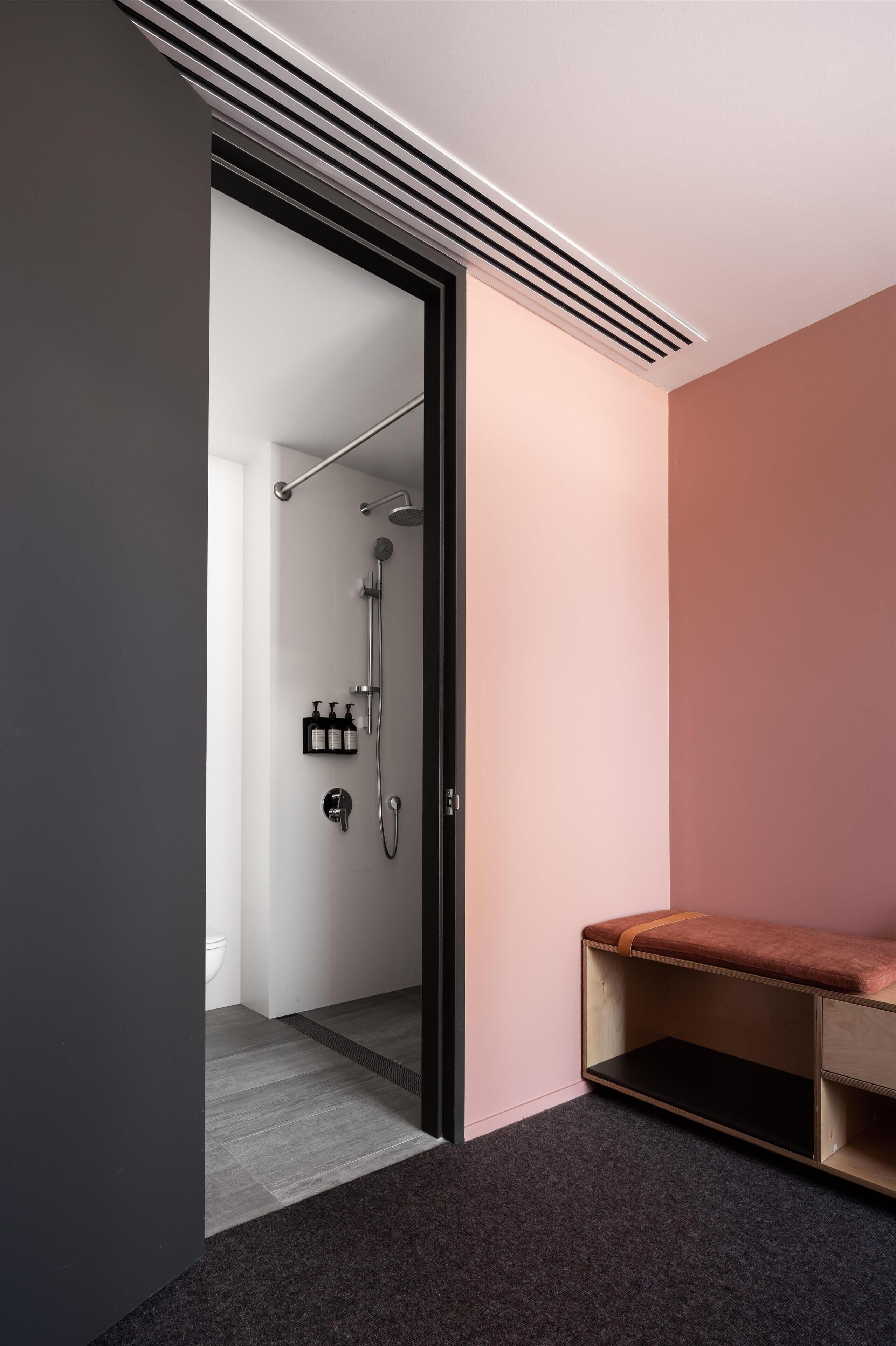 A modern bathroom with a shower, toilet, and storage cabinet.