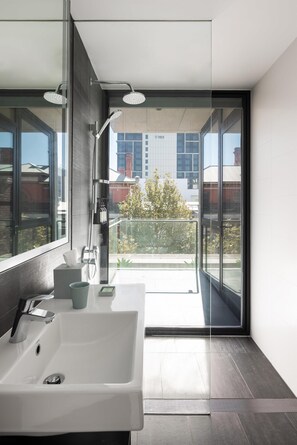 A modern bathroom with a large mirror, a white sink, and a glass-enclosed shower area.