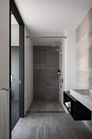 A modern bathroom with a walk-in shower, a large mirror, and a minimalist design.