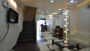 A hotel lobby with a staircase, a reception desk, a sofa, and a glass table. - Hotel Central Residency (Varanasi)