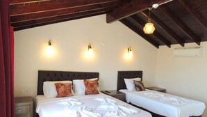 A hotel room with two beds, each with a headboard and pillows, a nightstand, and a wall-mounted air conditioning unit. - Villa Dreams (Selçuk)