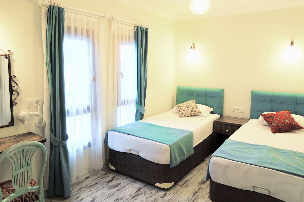 A hotel room with two beds, a chair, a desk, and a mirror.
