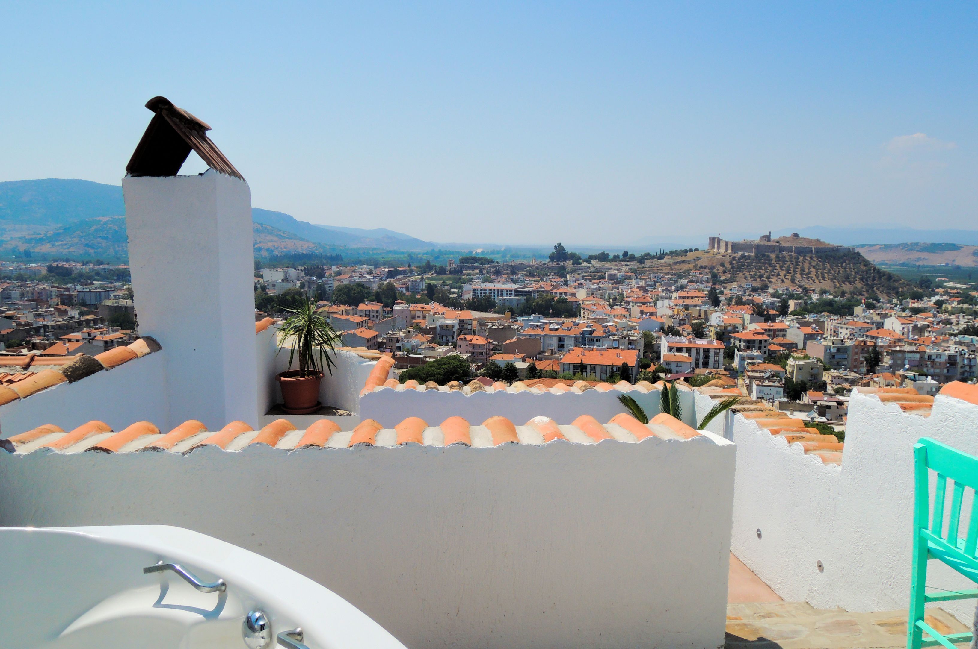 Eine Dachterrasse mit Blick auf eine Stadtlandschaft, darunter ein Hügel mit einer festungsähnlichen Struktur.