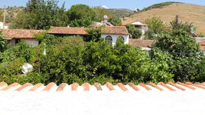 A hillside village with terracotta-tiled houses, lush greenery, and a clear blue sky. - Villa Dreams (Selçuk)
