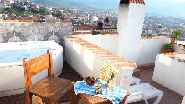 A rooftop terrace with a hot tub, wooden furniture, and a table with a checkered tablecloth. - Villa Dreams (Selçuk)