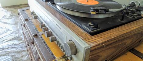 A turntable with a vinyl record on it, placed on a wooden table.