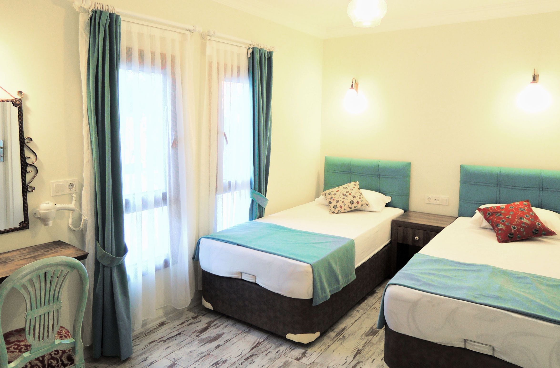 A room with two beds, a chair, a desk, and a mirror.