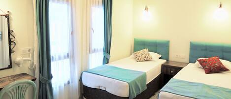 A room with two beds, a chair, a desk, and a mirror.