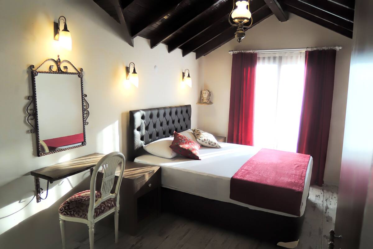 A bedroom with a large bed, a desk, a chair, and a mirror.