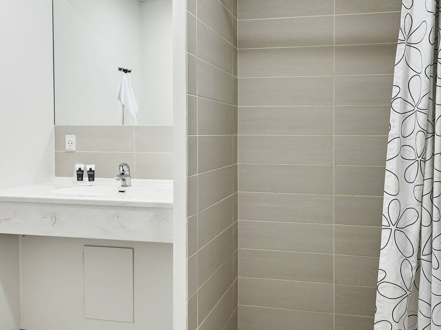 Un bagno con doccia, lavandino e specchio.