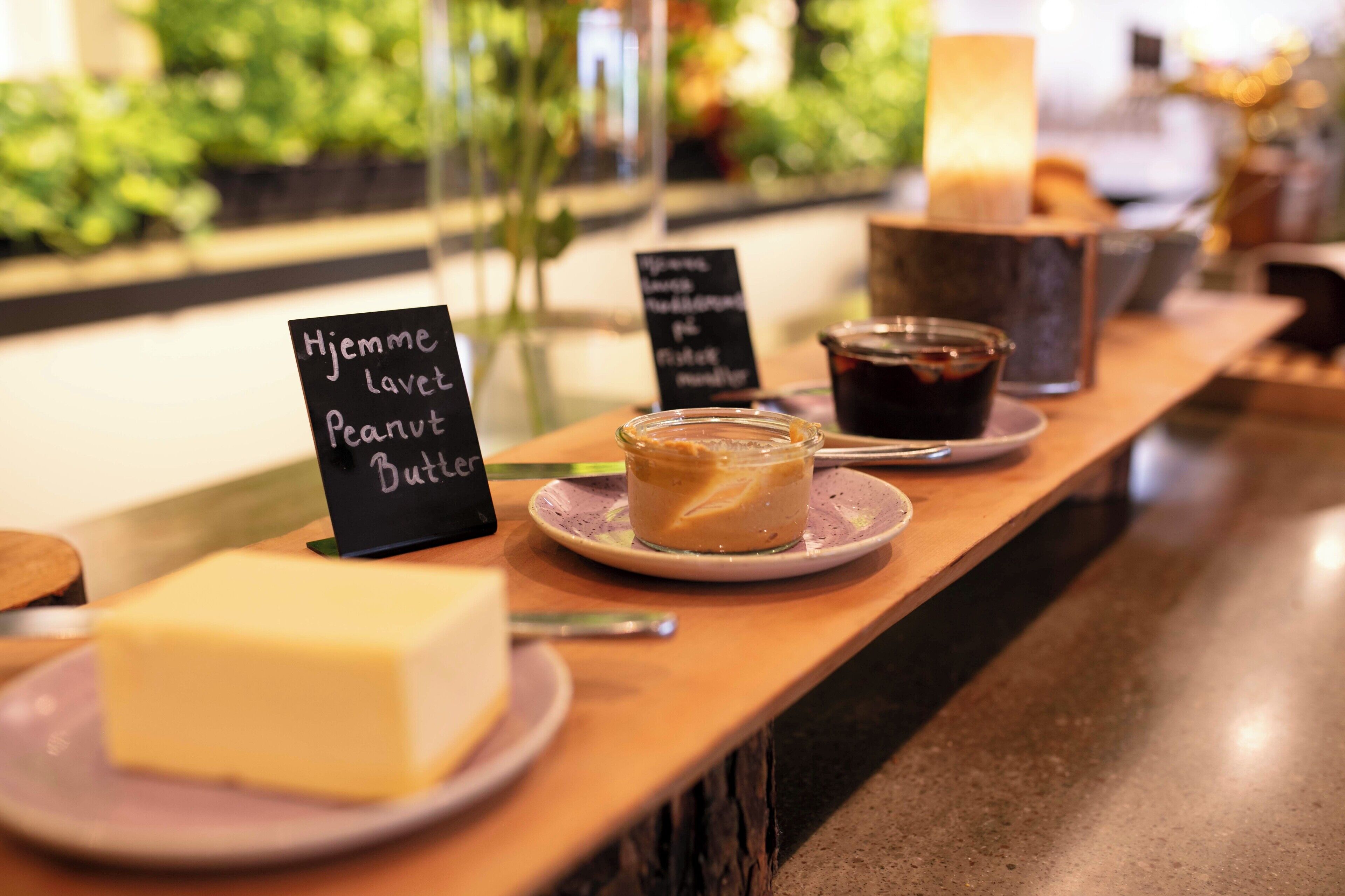 Una presentación de postres con un cartel que indica 'Hjemme lavet Peanut Butter' y un tarro de mantequilla de maní.