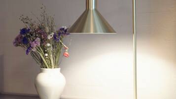 A desk with a vase of flowers, a lamp, and a remote control.