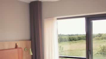 Un dormitorio con cama, lámpara, vistas al exterior y una ventana.
