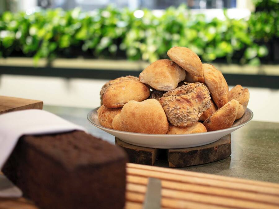 A plate of assorted bread rolls on a wooden surface with a knife beside it.