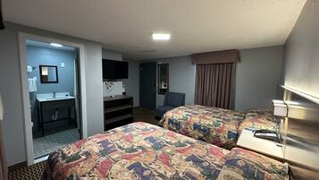 Habitación de hotel con dos camas, un escritorio, una silla, un televisor y un baño.