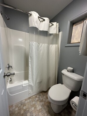A bathroom with a bathtub, toilet, and a shower curtain.