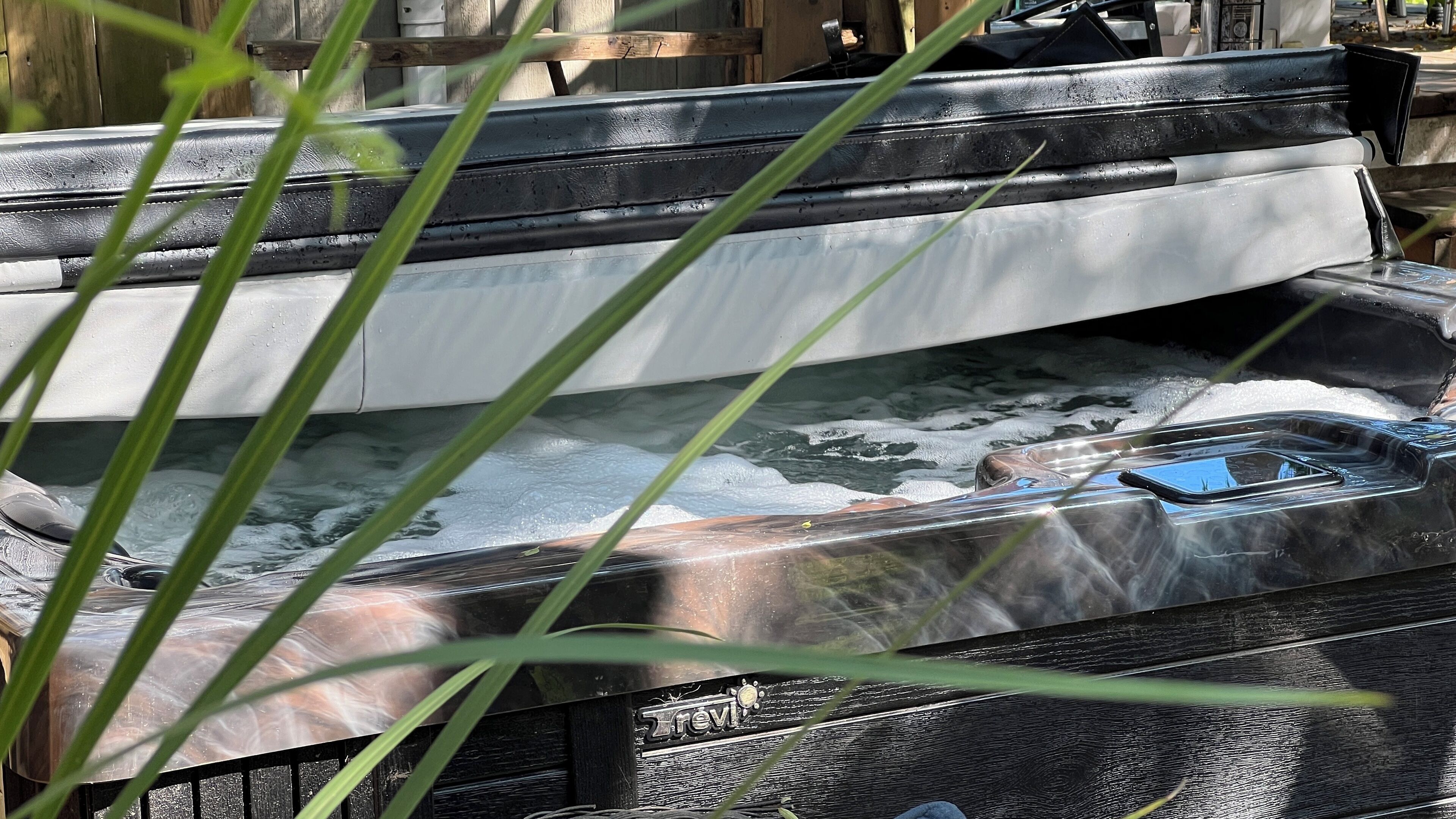 A vehicle with a black and white exterior, parked outdoors with visible water and foam, surrounded by greenery.