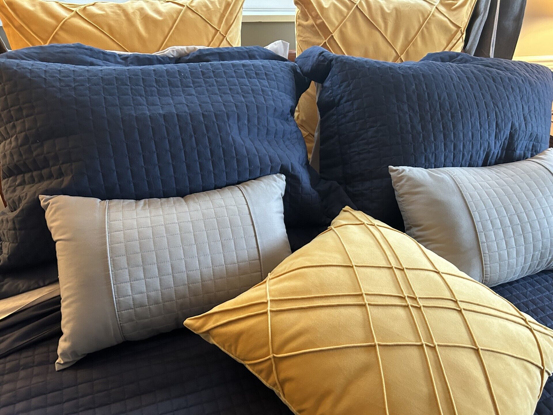 A bed with multiple pillows in various colors and textures.