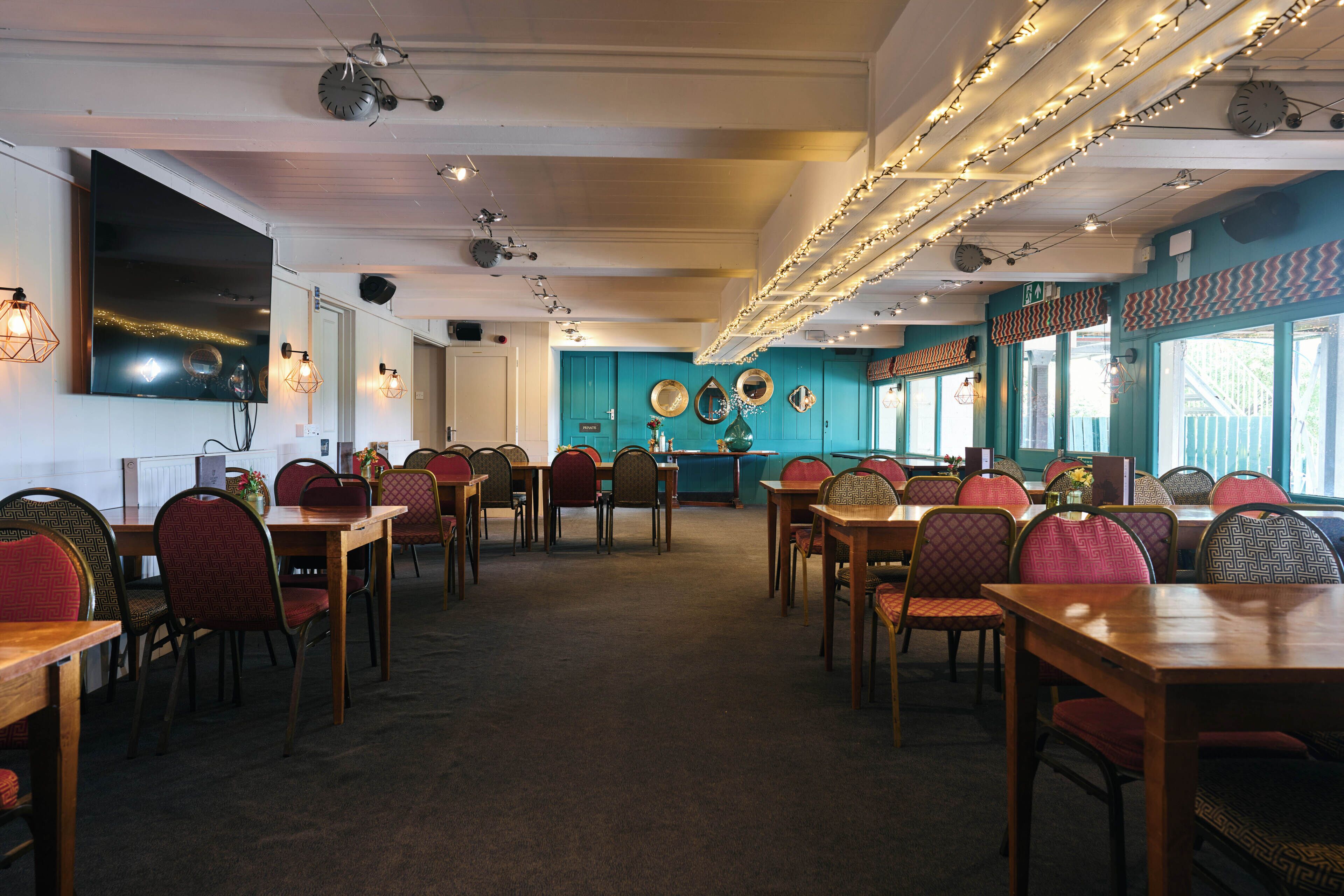 Un restaurant amb diverses taules i caires, una zona de bar i miralls decoratius a la paret.