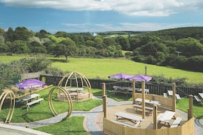 Relax in a serene outdoor setting with a grassy area, wooden deck, and picnic tables.