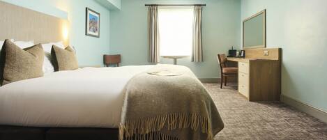 Una habitación de hotel con una cama grande, un escritorio, una silla, un aparador y una ventana con cortinas.