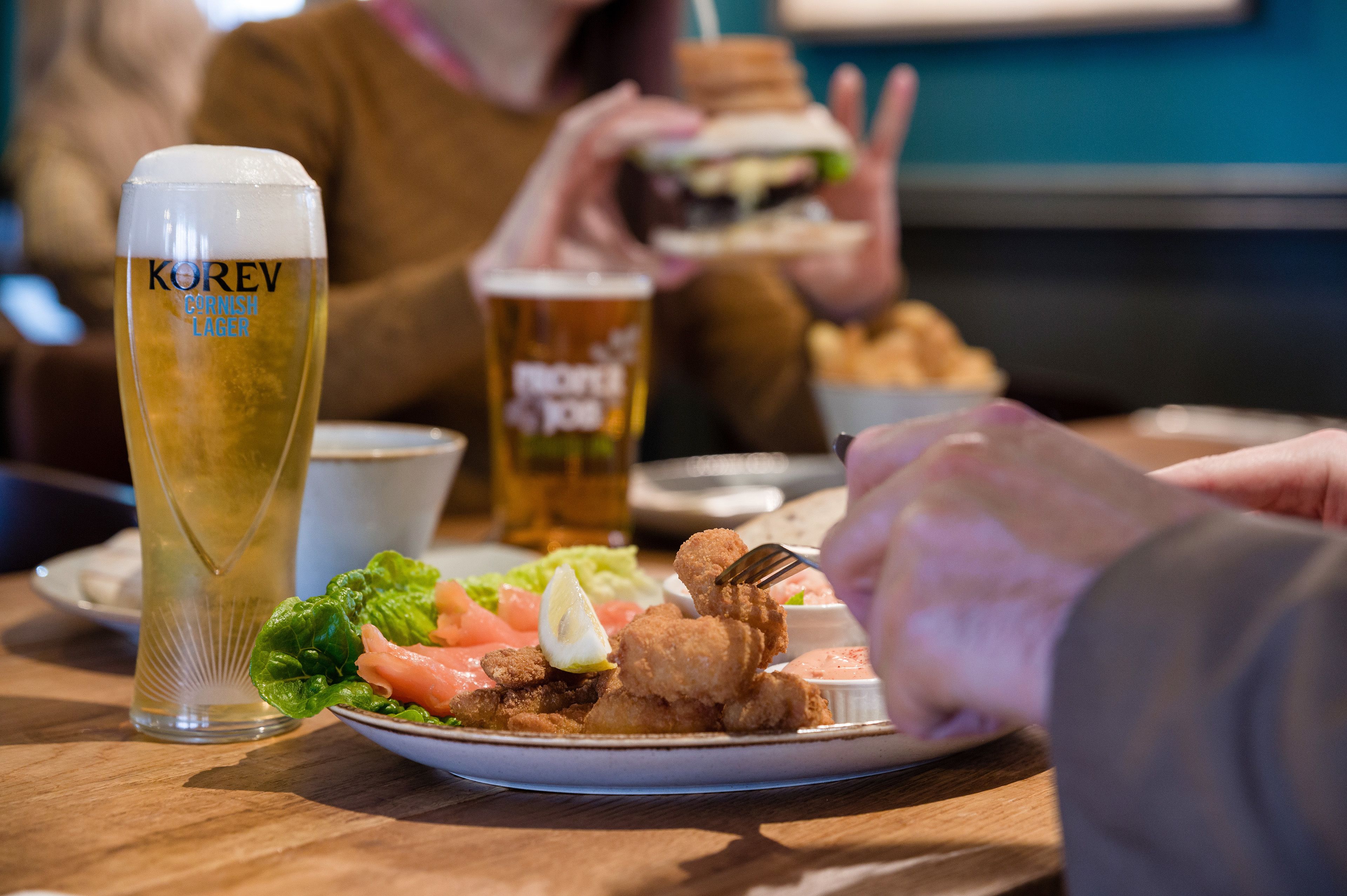 A dining table with a plate of food, a glass of beer, and a cup.
