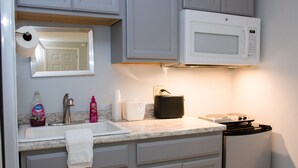 A kitchen with a microwave, sink, and cabinets. - Seacoast Motel (Wells)