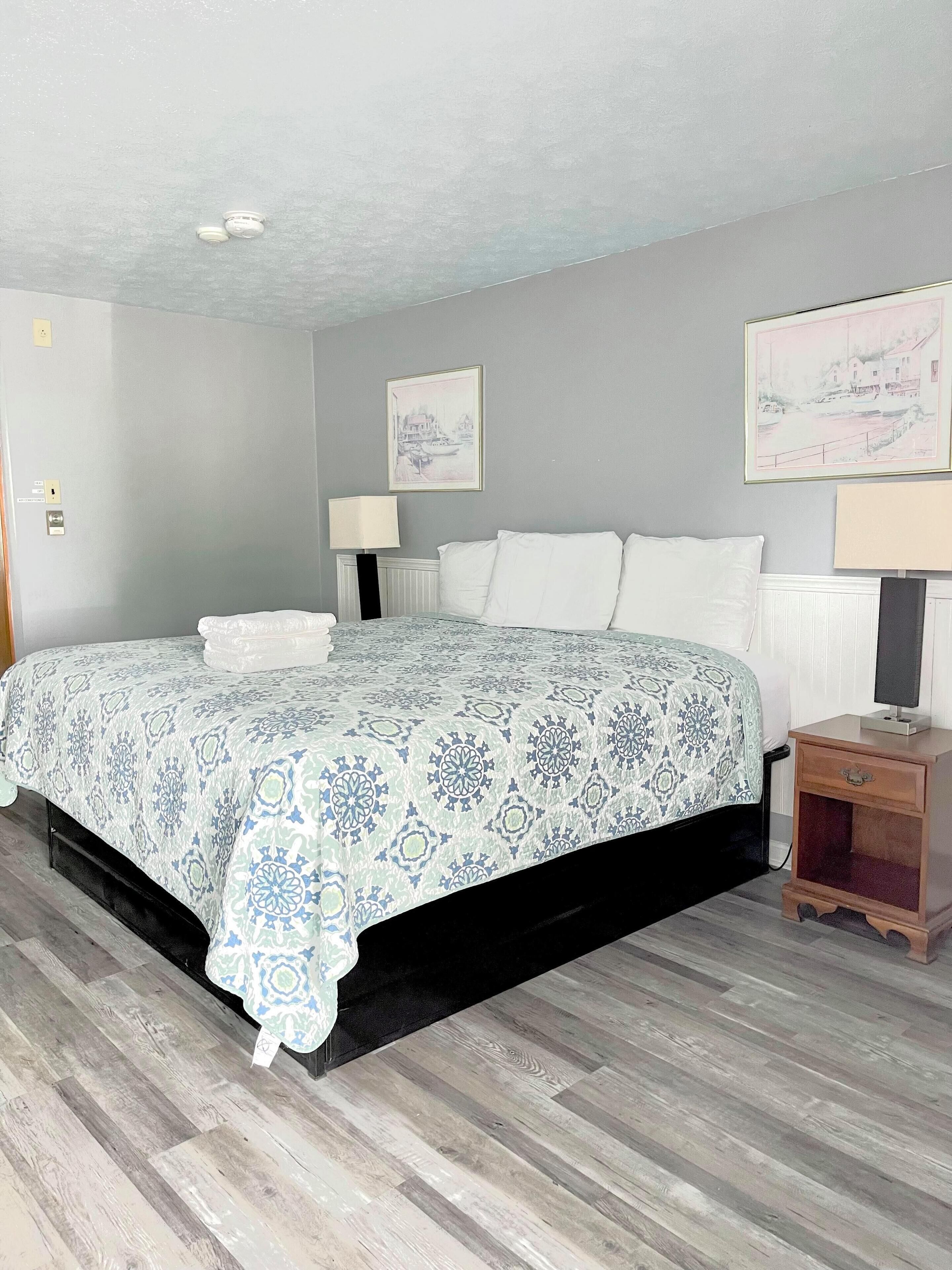 A bedroom with a bed, bedside tables, and artwork on the walls.