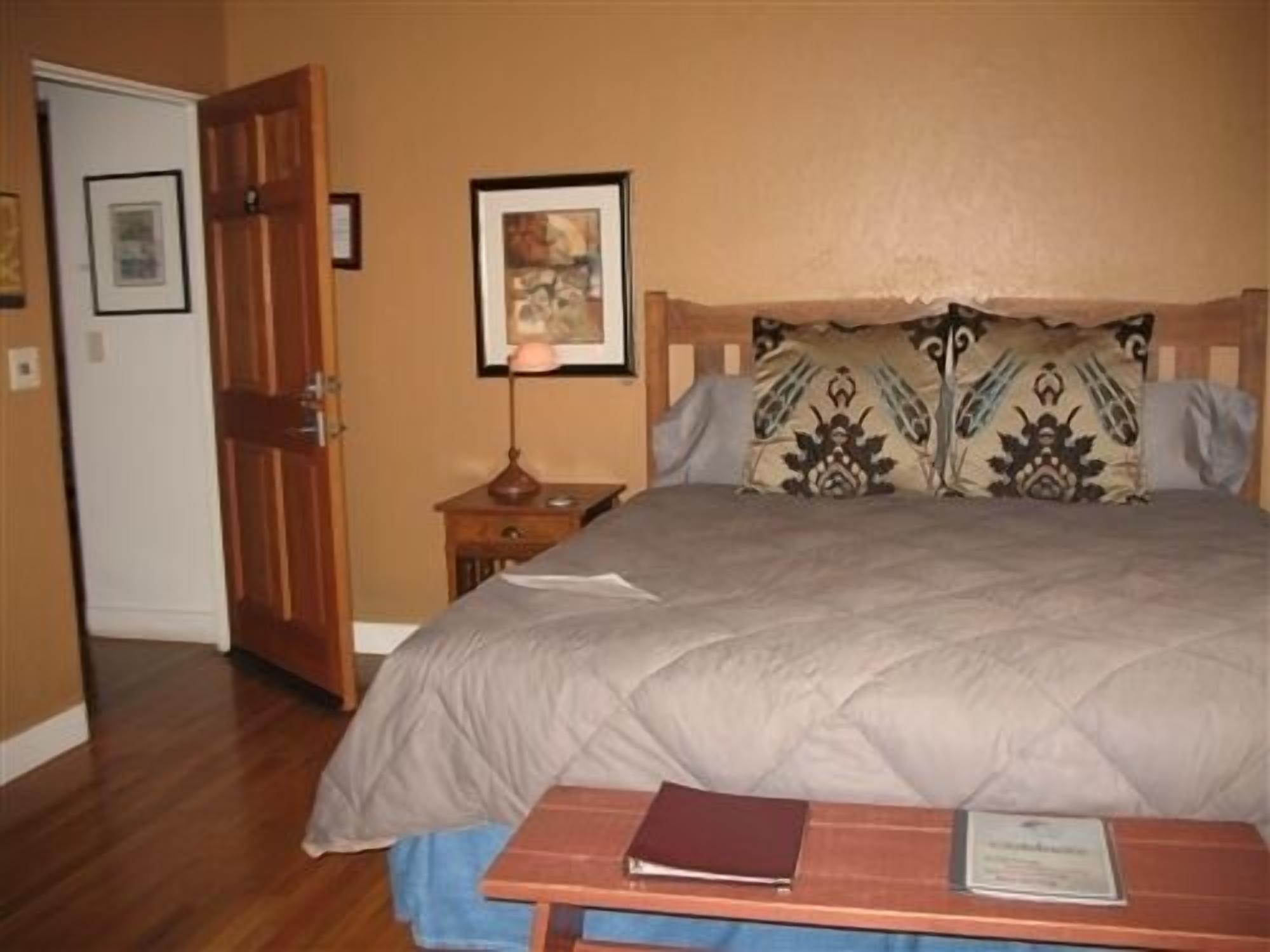 A bedroom with a bed, a nightstand, a lamp, and a wooden door.