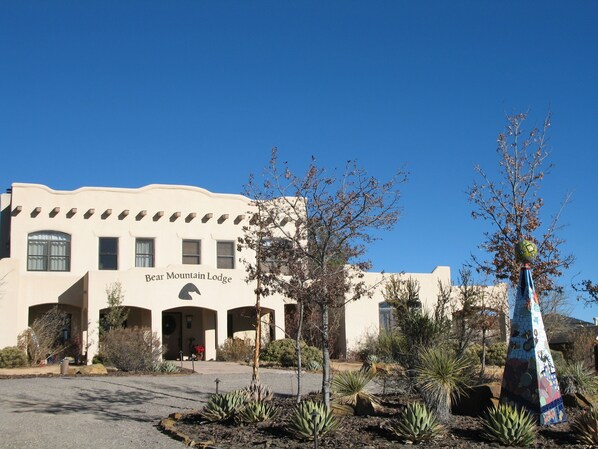 Bear Mountain Lodge met heldere lucht, een cactusgaard en een kleurrijk beeldhouwwerk.