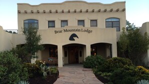 The exterior of Bear Mountain Lodge with a stone pathway leading to the entrance, surrounded by landscaped greenery. - Bear Mountain Lodge (Silver City)