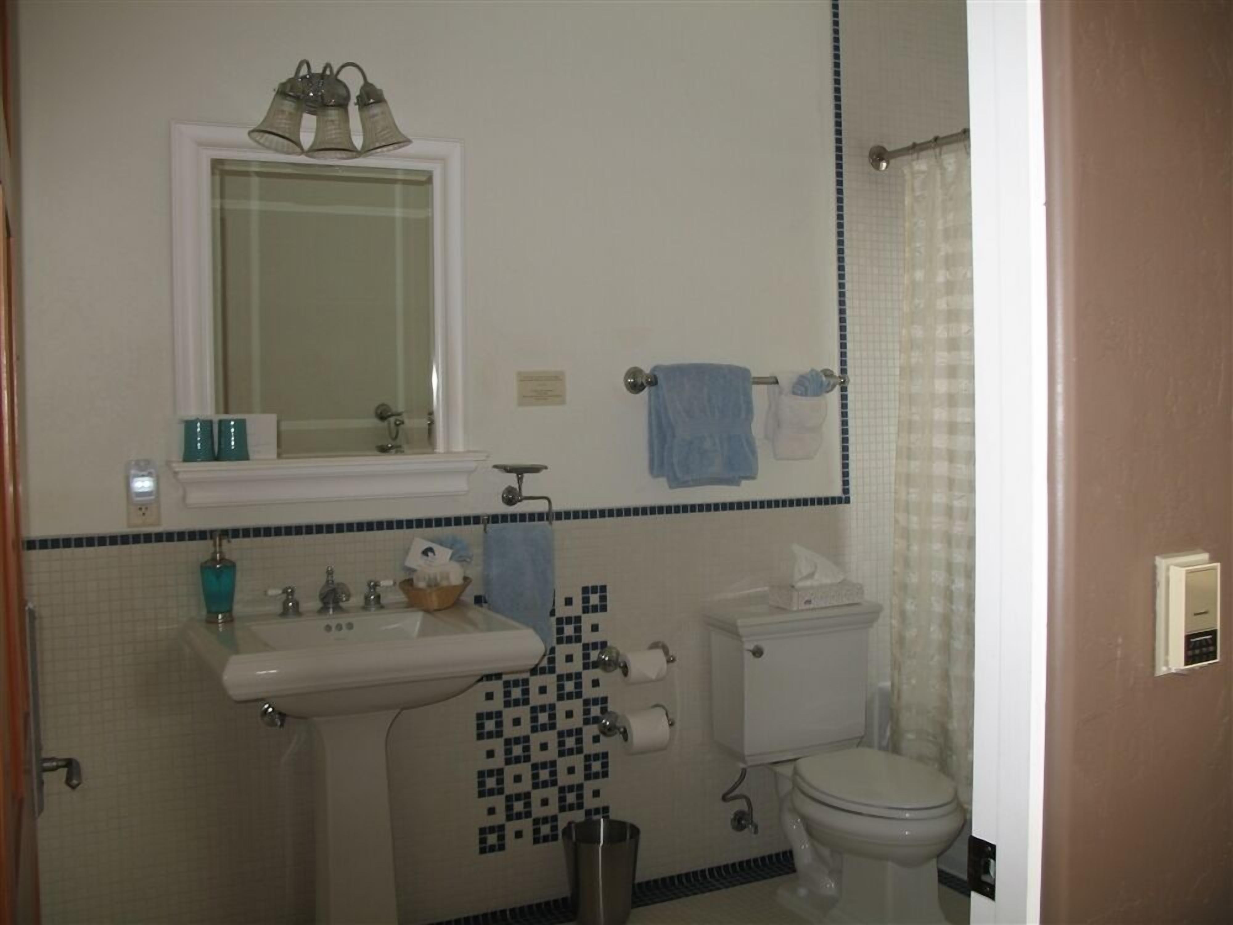 Une salle de bain équipée d’un lavabo, d’un miroir, de toilettes et d’un porte-serviettes.