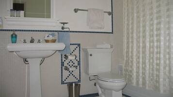 A bathroom with a pedestal sink, toilet, and a small trash can.