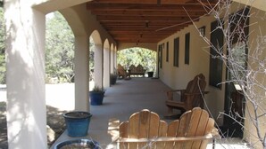 A covered outdoor seating area with wooden benches and potted plants. - Bear Mountain Lodge (Silver City)